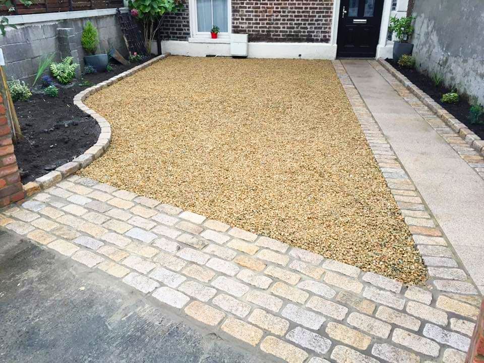 Gravel driveway with brick edging and a small flower bed.