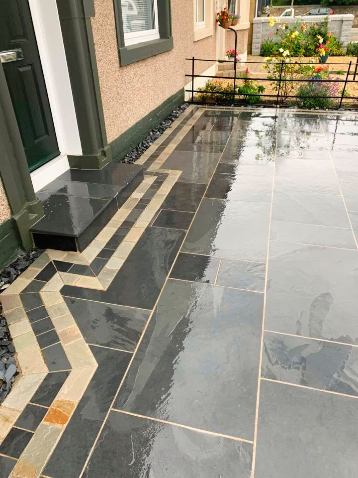 Exterior with wet, dark gray slate tiles. Entryway step has a decorative, patterned border.