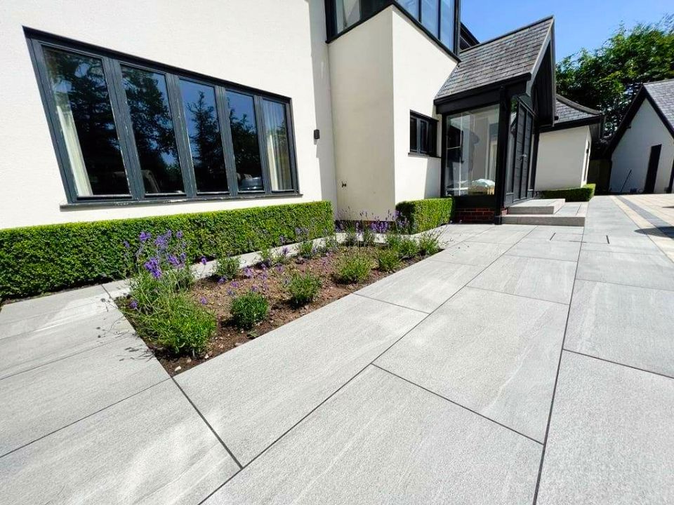 Exterior view of a modern white house with a stone pathway and manicured hedges.