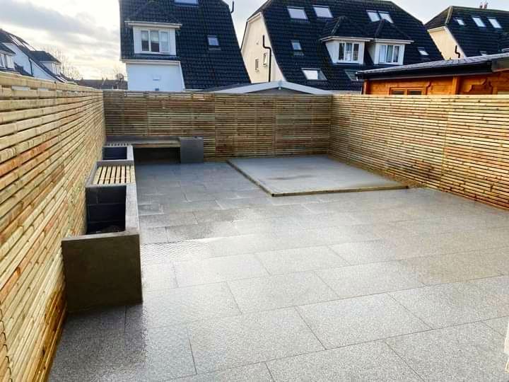 A modern rooftop patio with brick walls, grey stone floor, and built-in benches.