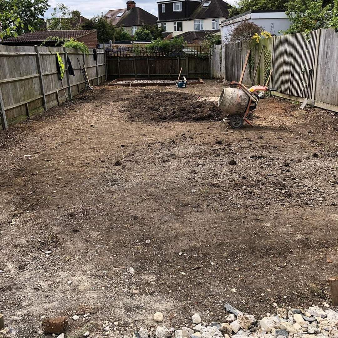 Cleared backyard with a pile of dirt, wheelbarrow, and wooden fences.