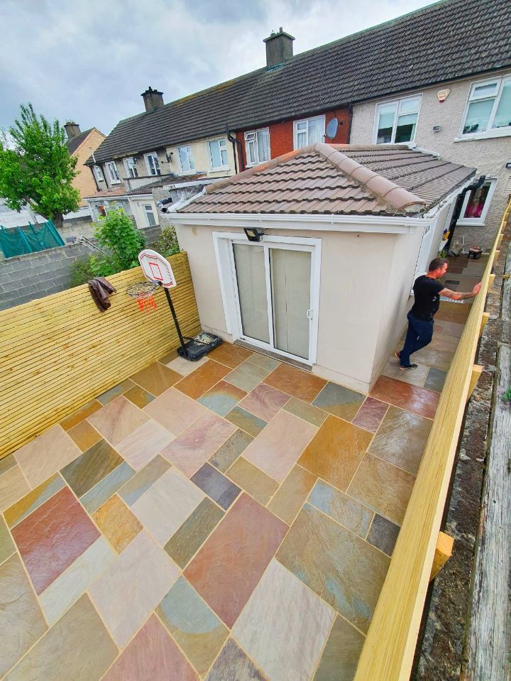 Stone patio with building and fence; person on right.