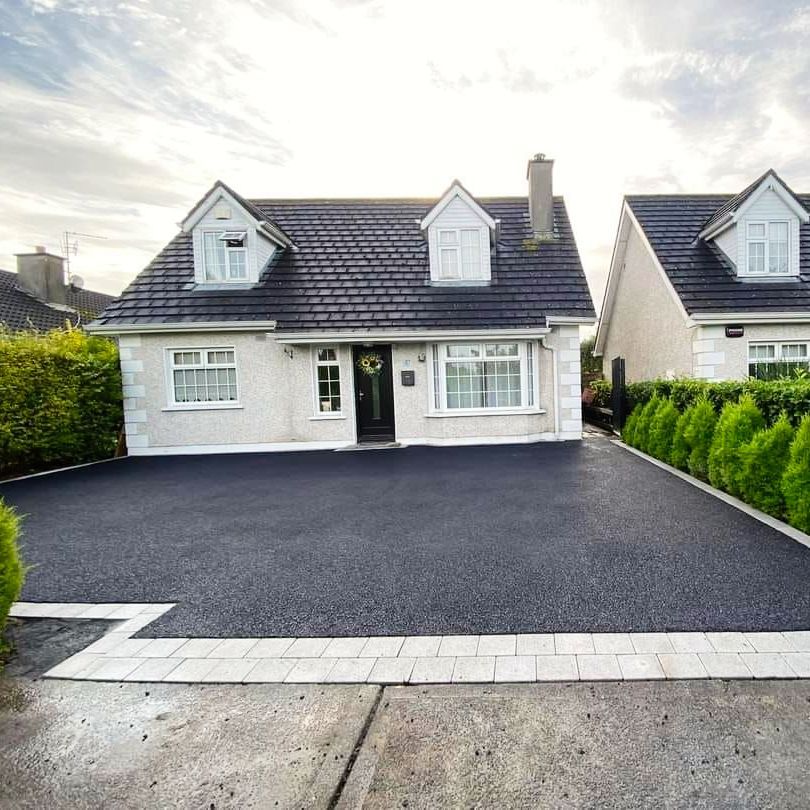 A white house with a black driveway in front of it