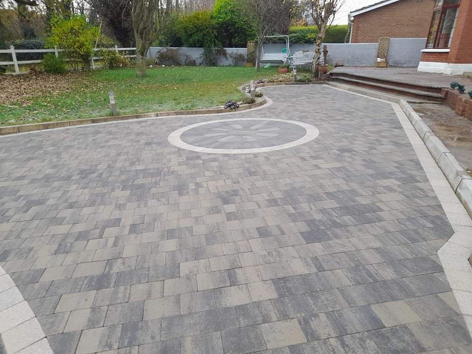 Brick patio with a circular design in a backyard setting.