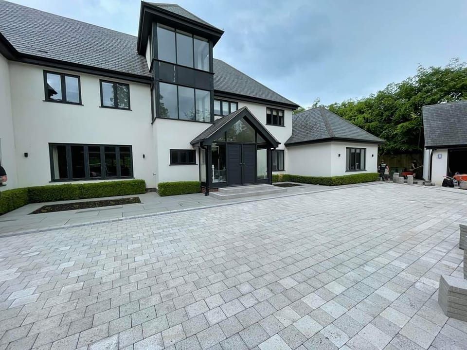 Modern white house with a paved driveway and large windows.