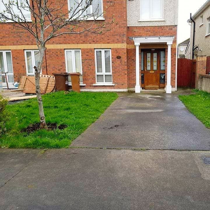 Brick house with front door, driveway, grass, and a bare tree.