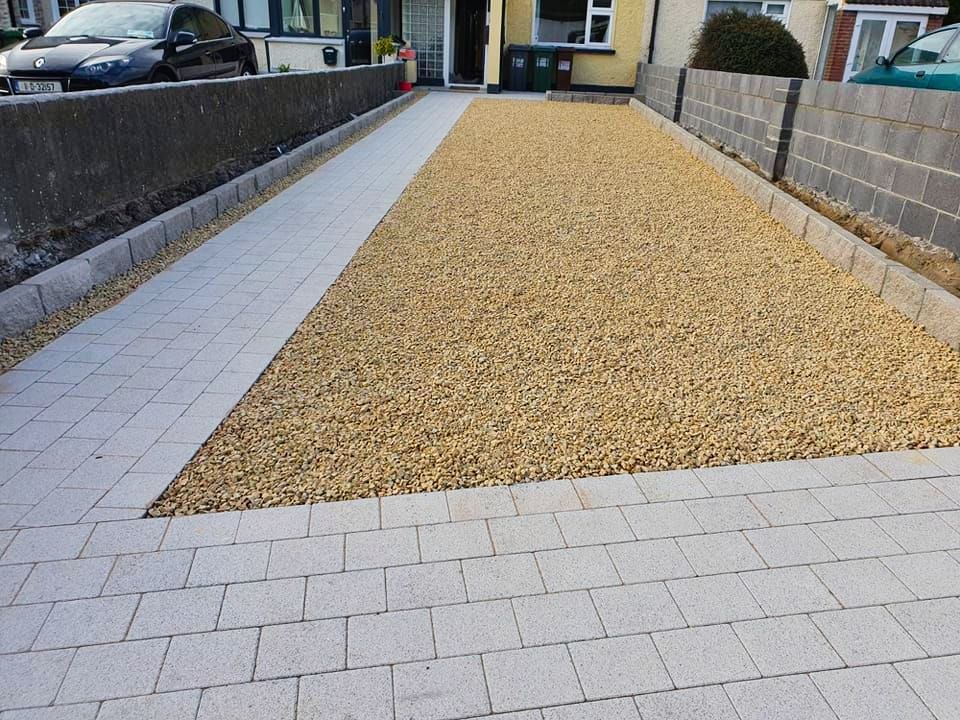 Driveway with gray pavers bordering tan gravel. A car is parked at the end.