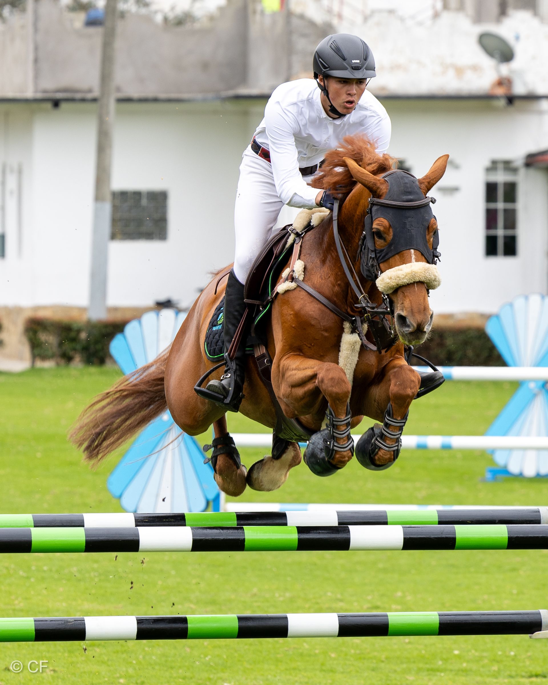A man is riding a brown horse over a jump