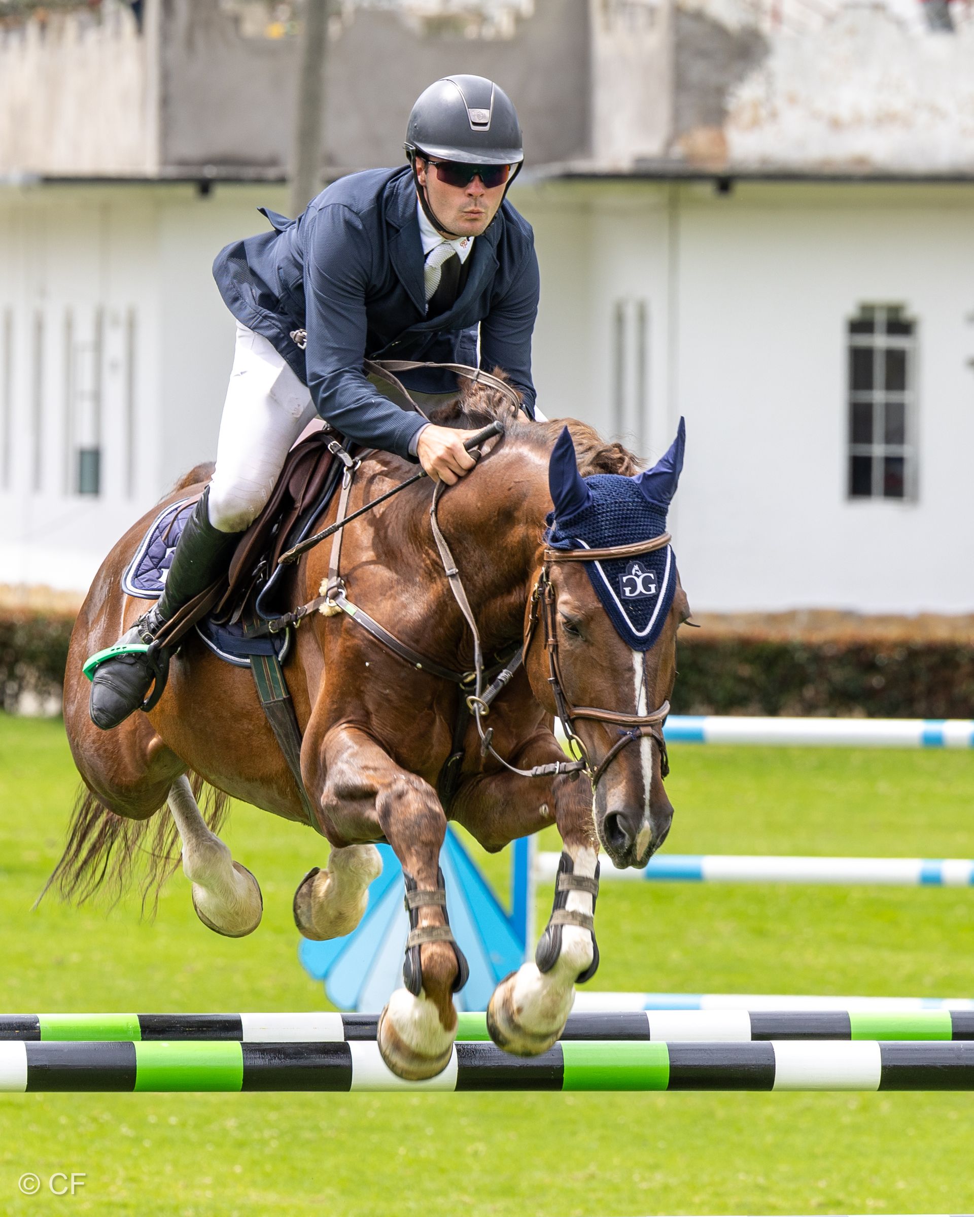 A man is riding a brown horse over a jump