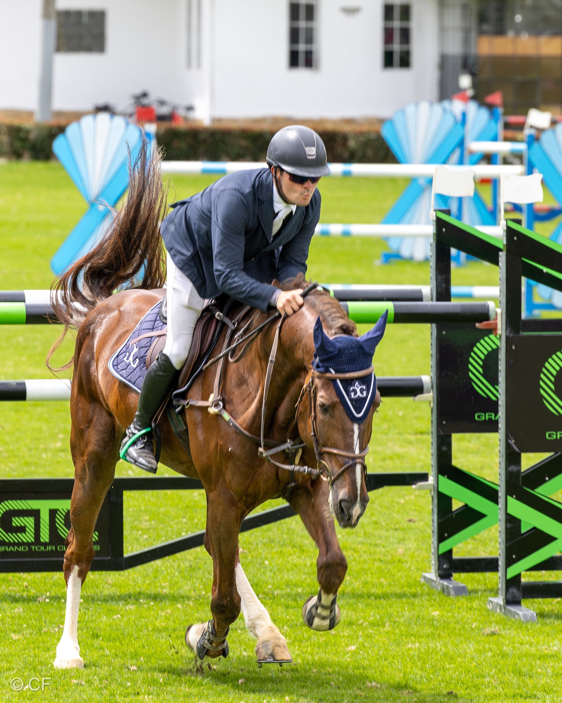 A man is riding a brown horse over a hurdle.