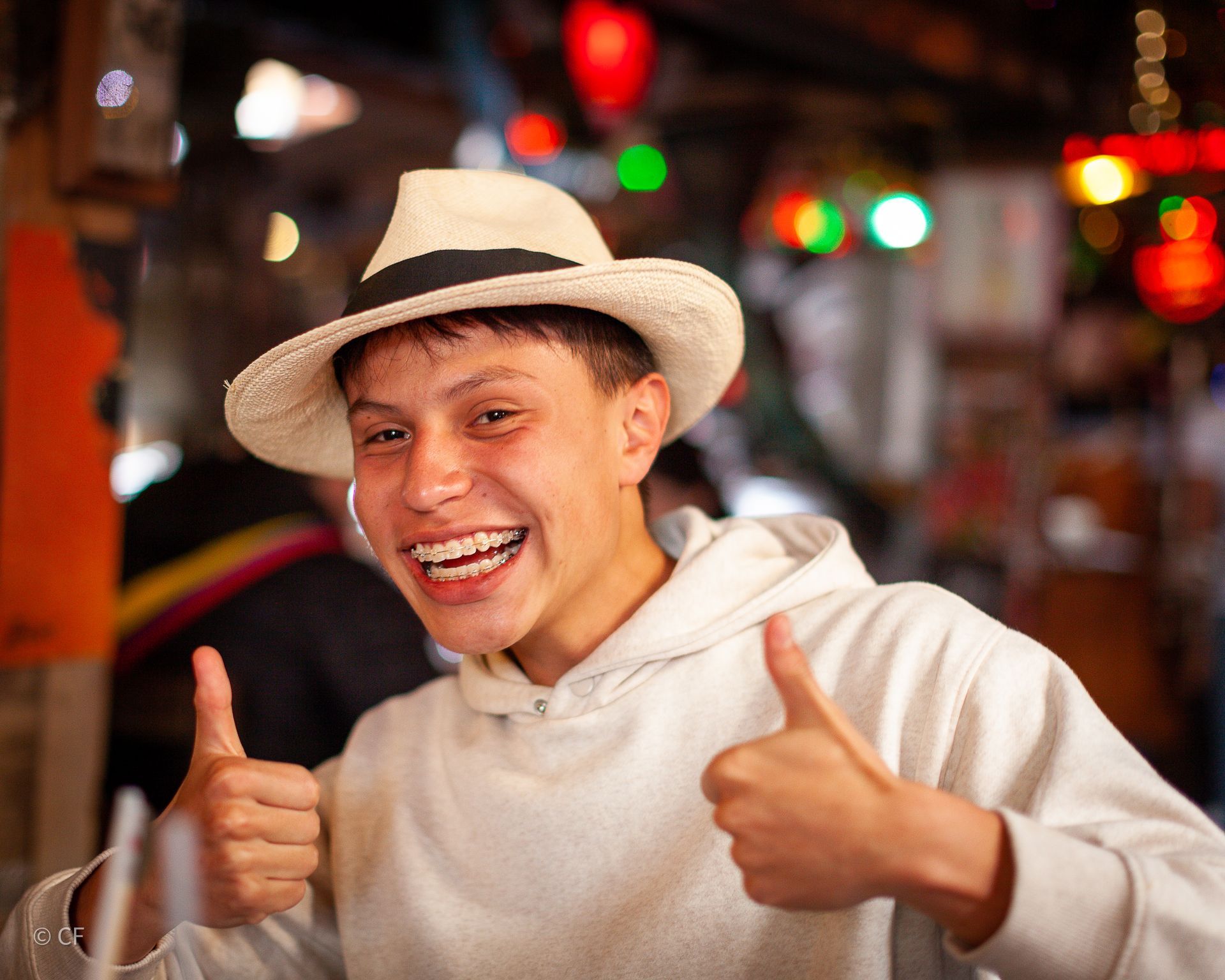 A young man wearing a hat is giving two thumbs up