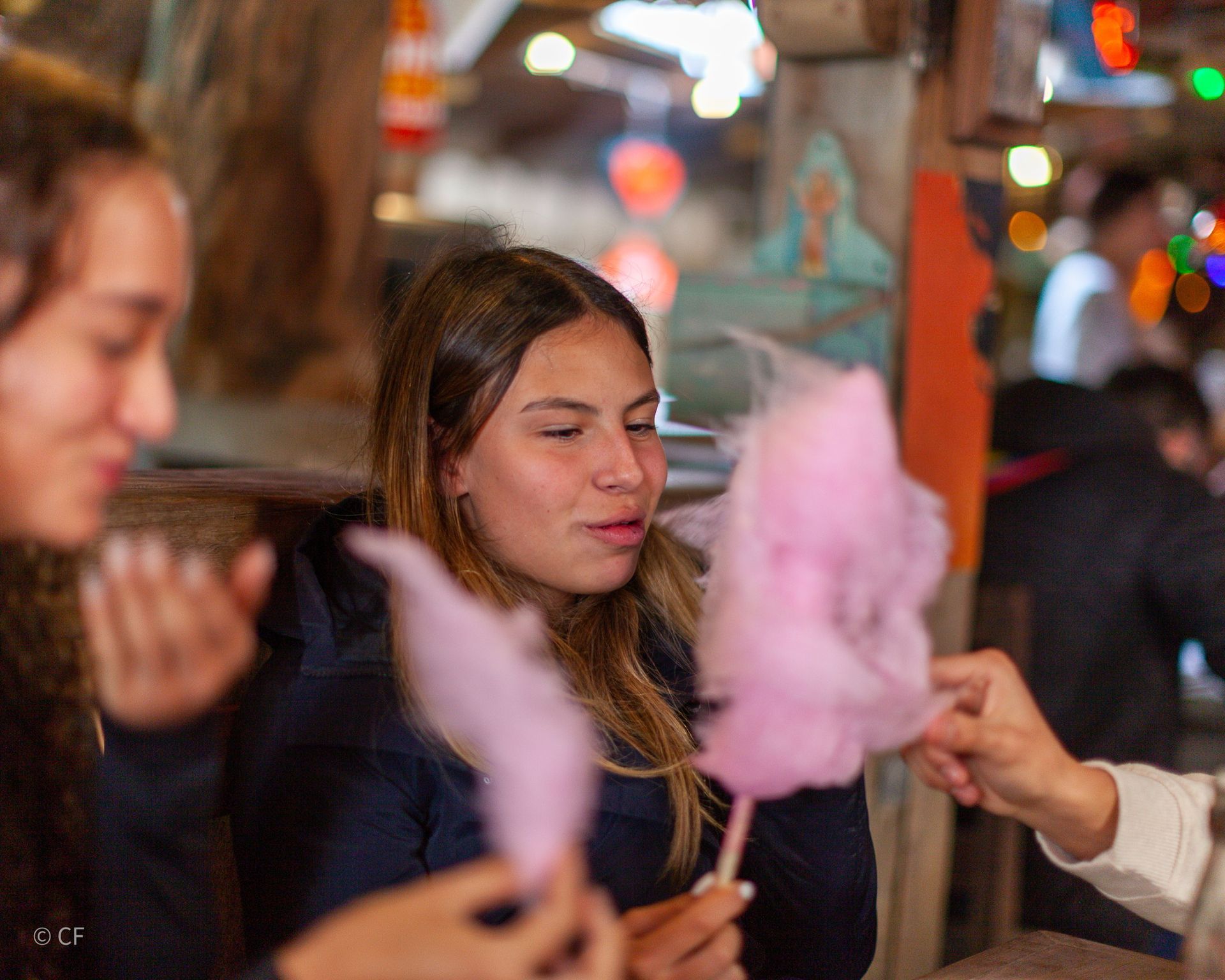 A woman is eating pink cotton candy in a restaurant.