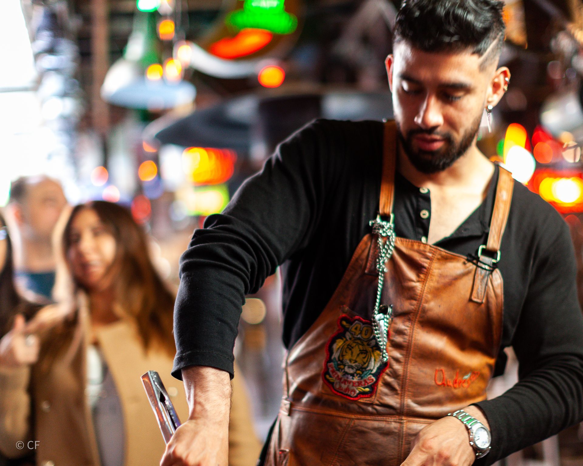 A man with a beard wearing an apron is standing in front of a crowd of people.