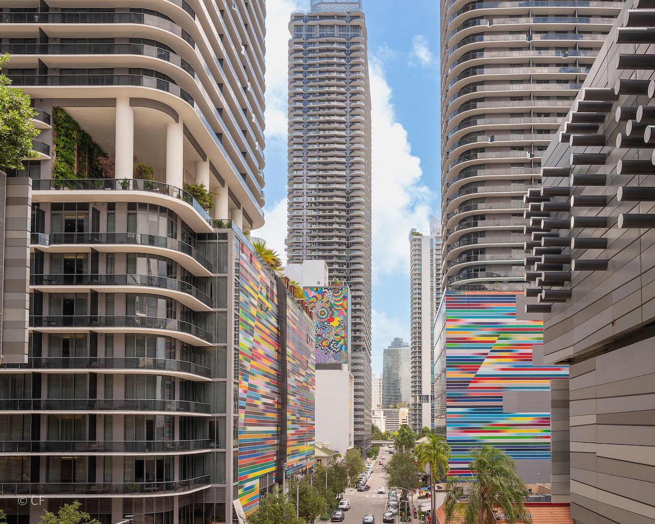 A city street with a lot of tall buildings and a colorful building in the middle.
