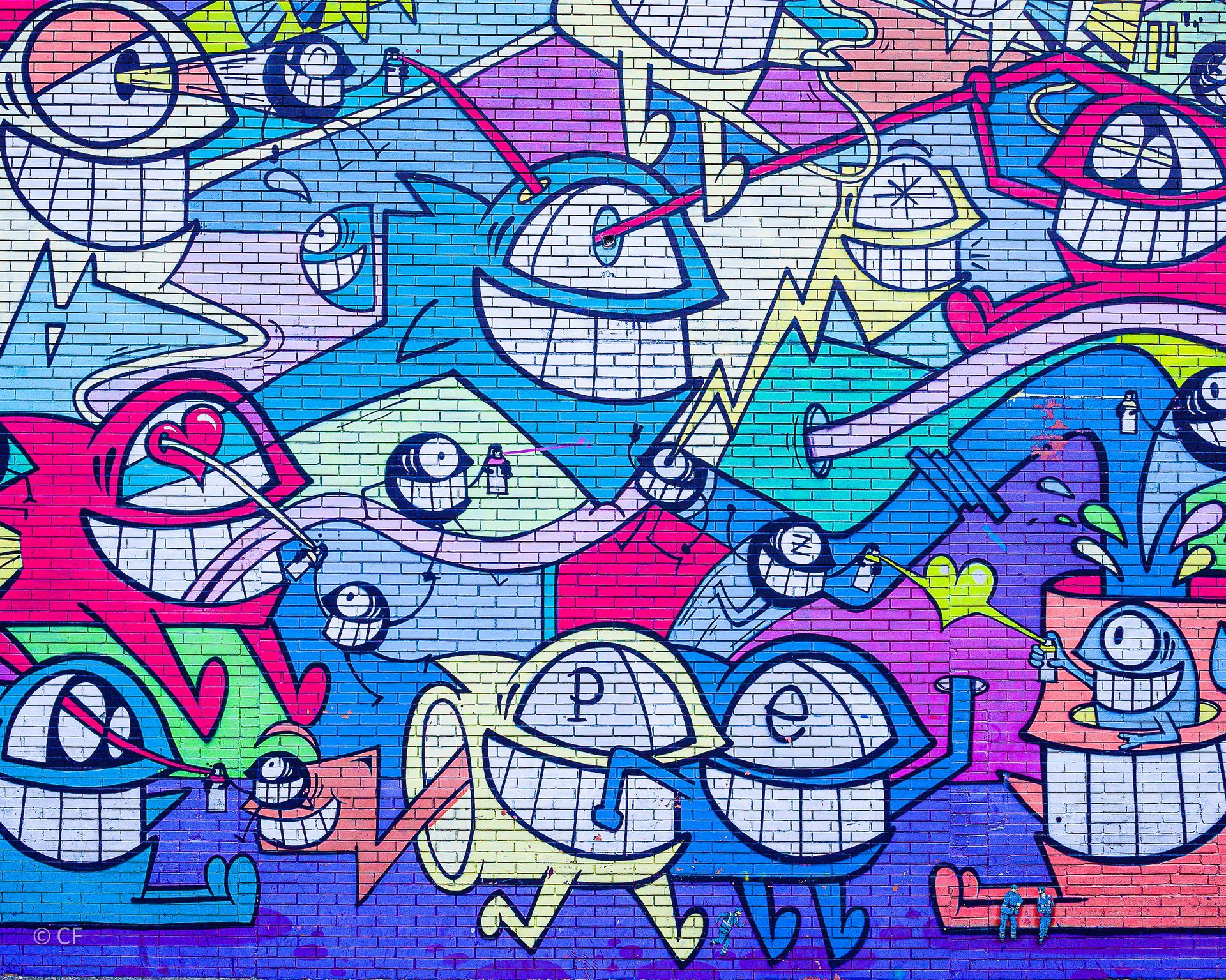 A colorful graffiti wall with a lot of cartoon characters on it.