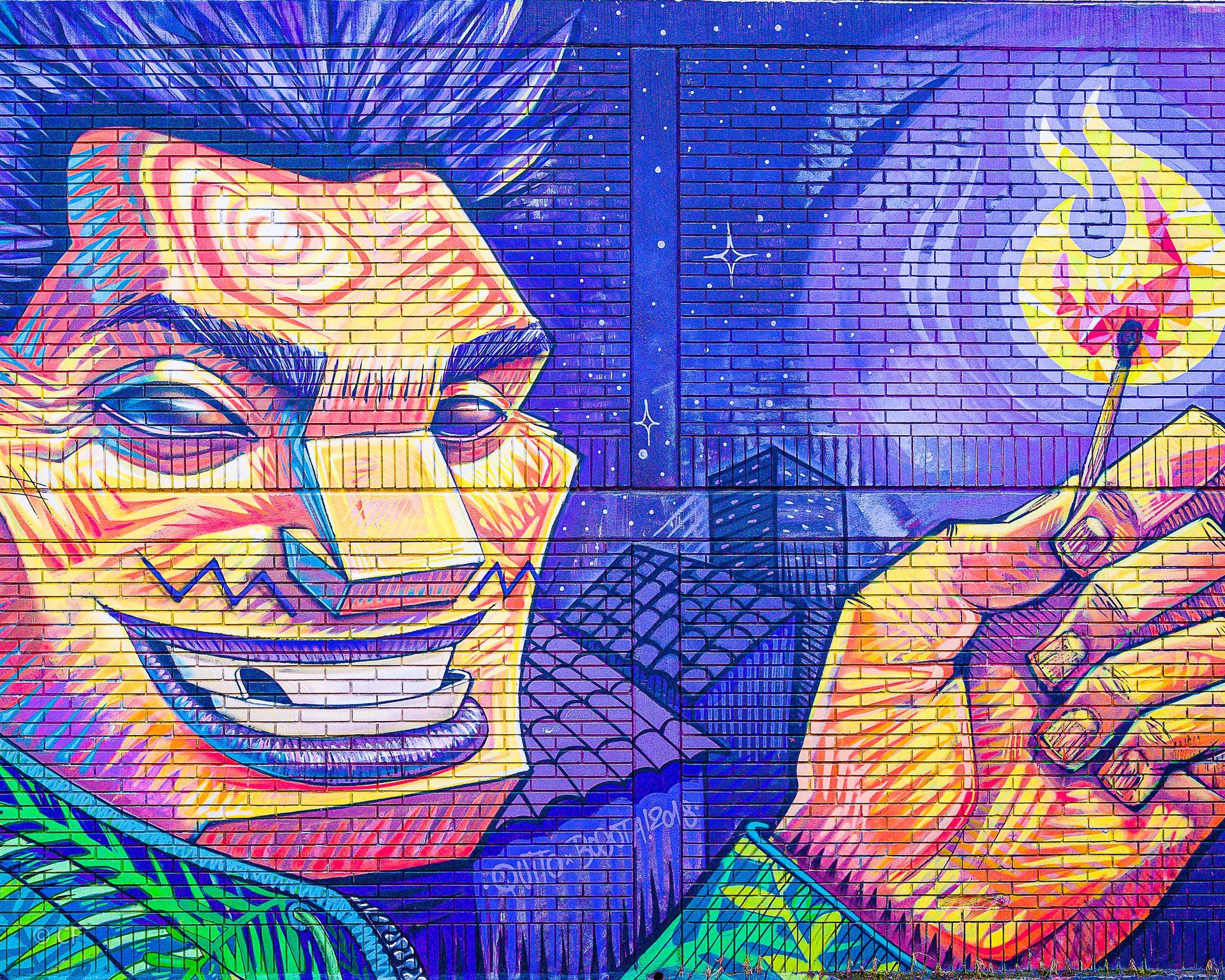 A colorful mural of a man holding a match on a brick wall.