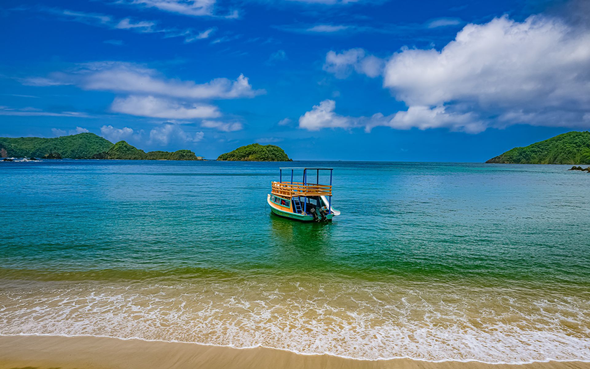 A boat is floating on top of a body of water near a beach.