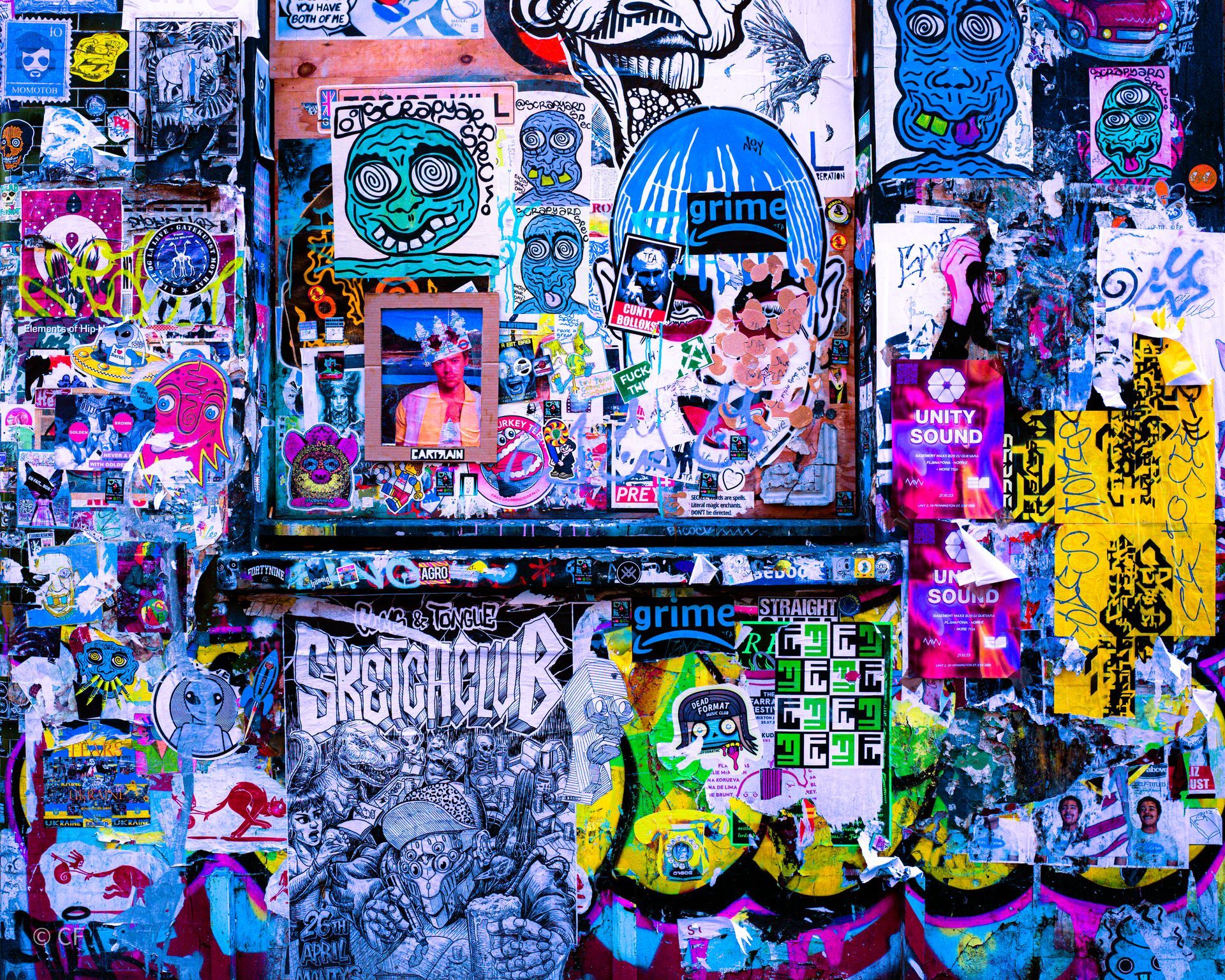 A wall covered in stickers including one that says grime