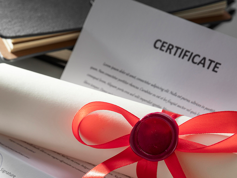 Certificate with a red ribbon and wax seal on a desk