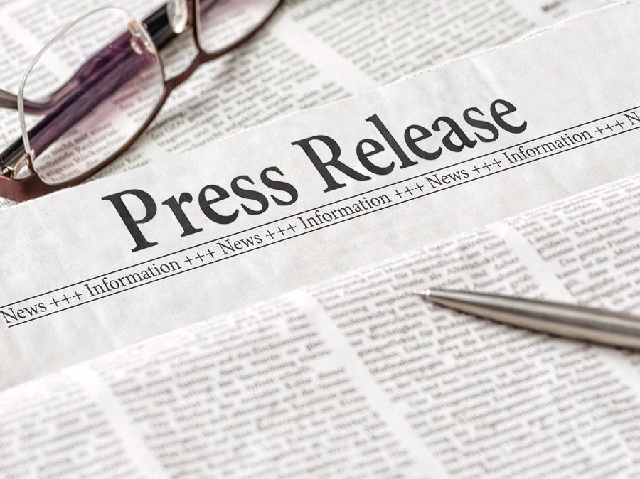Press release headline on newspaper with eyeglasses and pen nearby