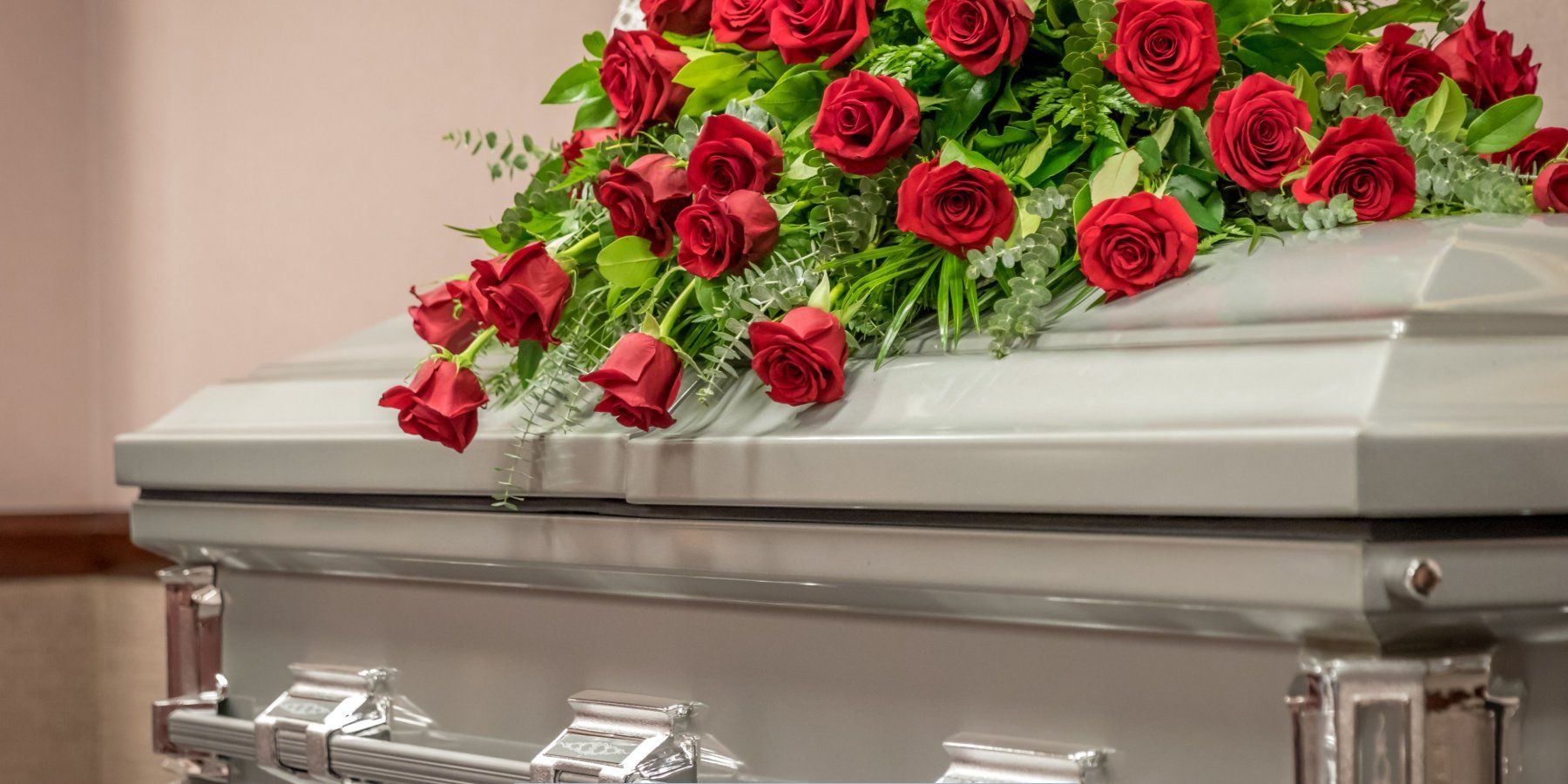 Silver casket adorned with a red rose spray during a memorial service at a Funeral Home and Cremations in Leominster, MA