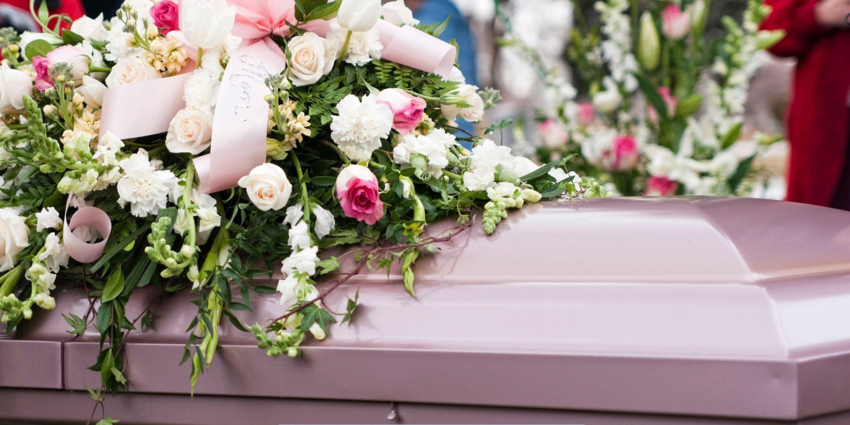 Pink casket adorned with elegant white and pink floral arrangement during a service at a Funeral Home and Cremations in Worcester, MA.