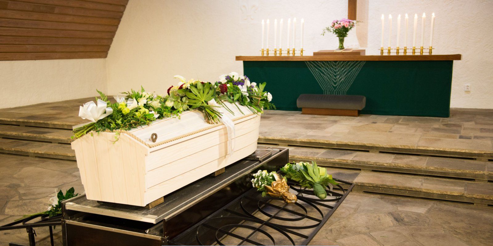 Casket with floral arrangements inside a chapel during a memorial service