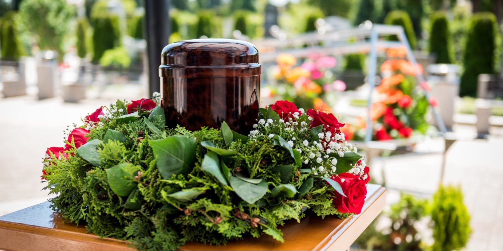 Urn surrounded by red roses and greenery at a memorial service