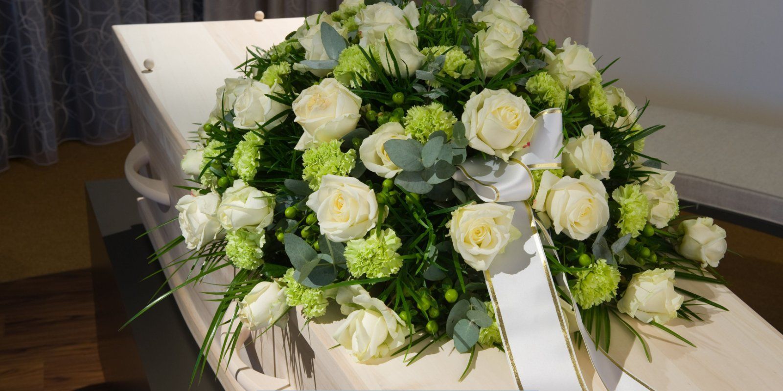 White rose floral arrangement on a casket at Funeral Home and Cremations in Shrewsbury, MA