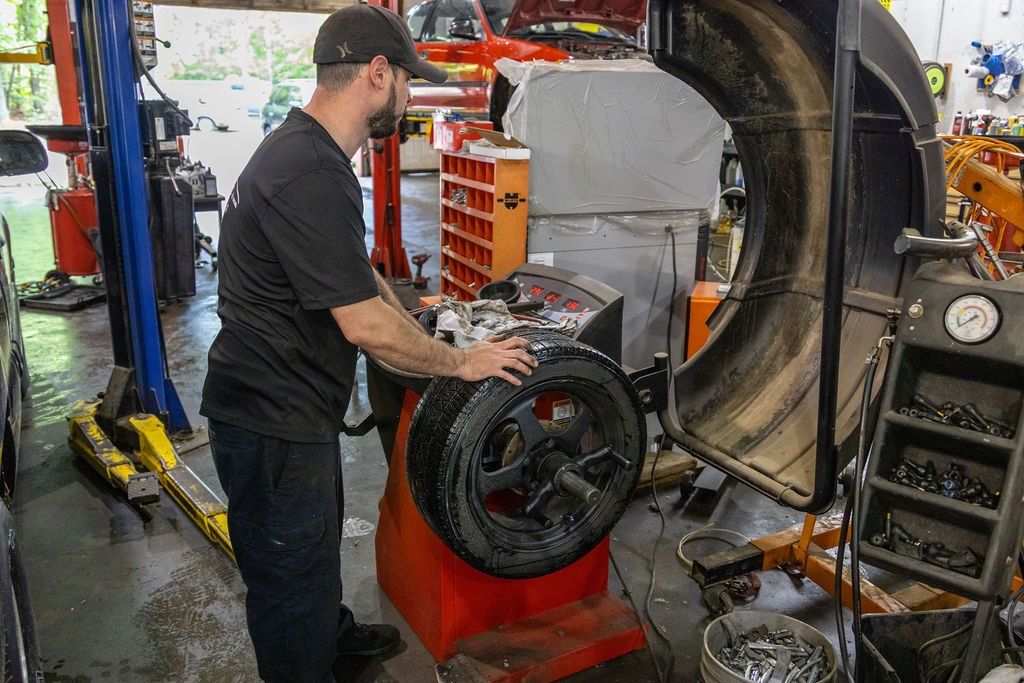 Mechanic balancing a car tire on a machine in a garage.