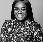A black and white photo of a woman wearing glasses and a floral shirt.