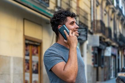 Man smiling while talking on a smartphone on a city street