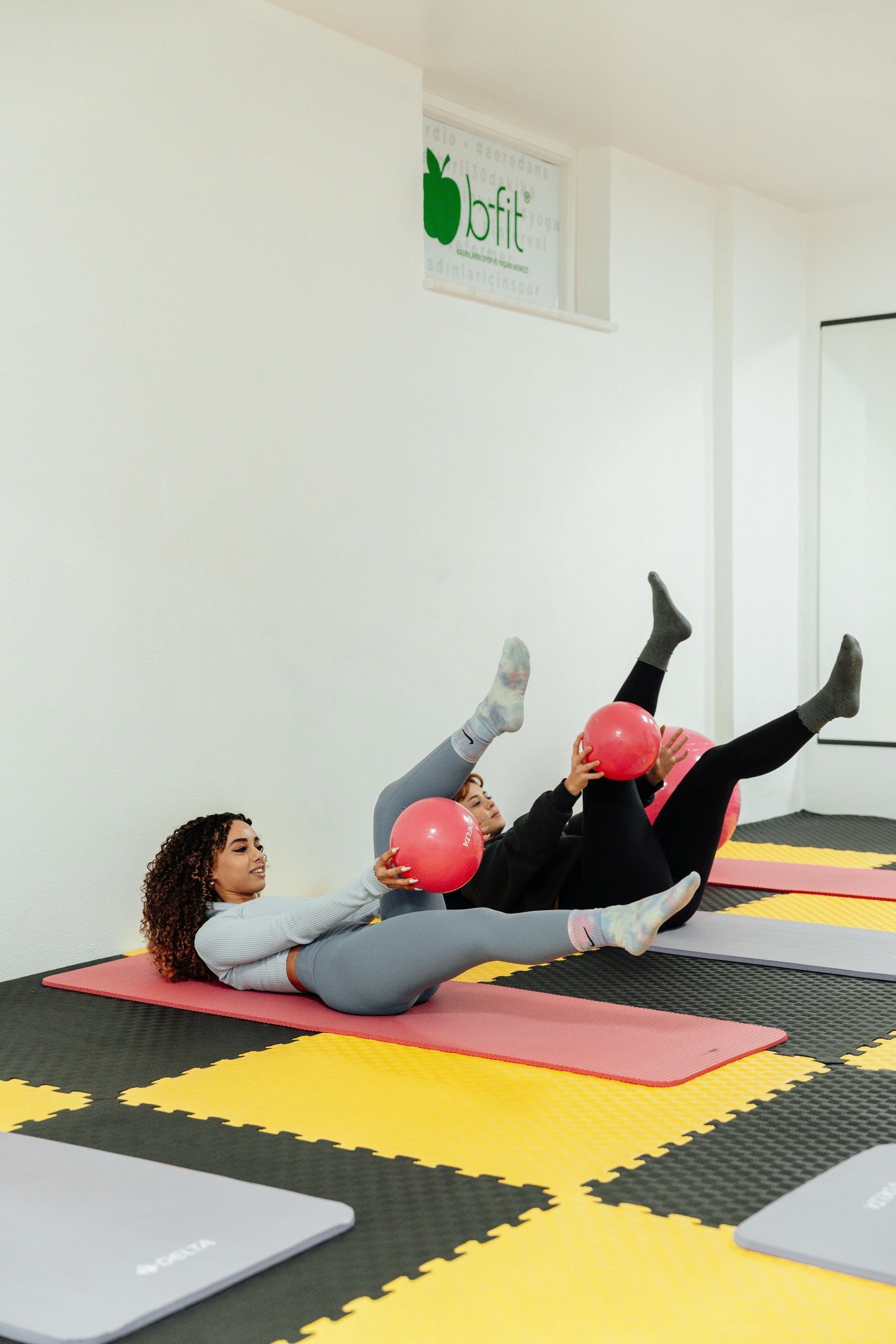 En gruppe kvinner gjør øvelser med pilatesballer i et treningsstudio.