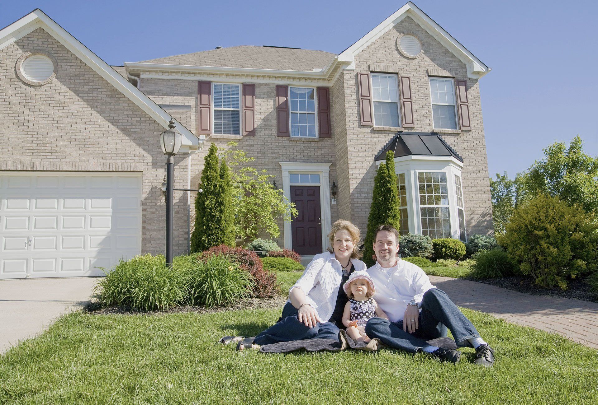 Happy Family Sitting on Lawn in Front of Buffalo, NY Home