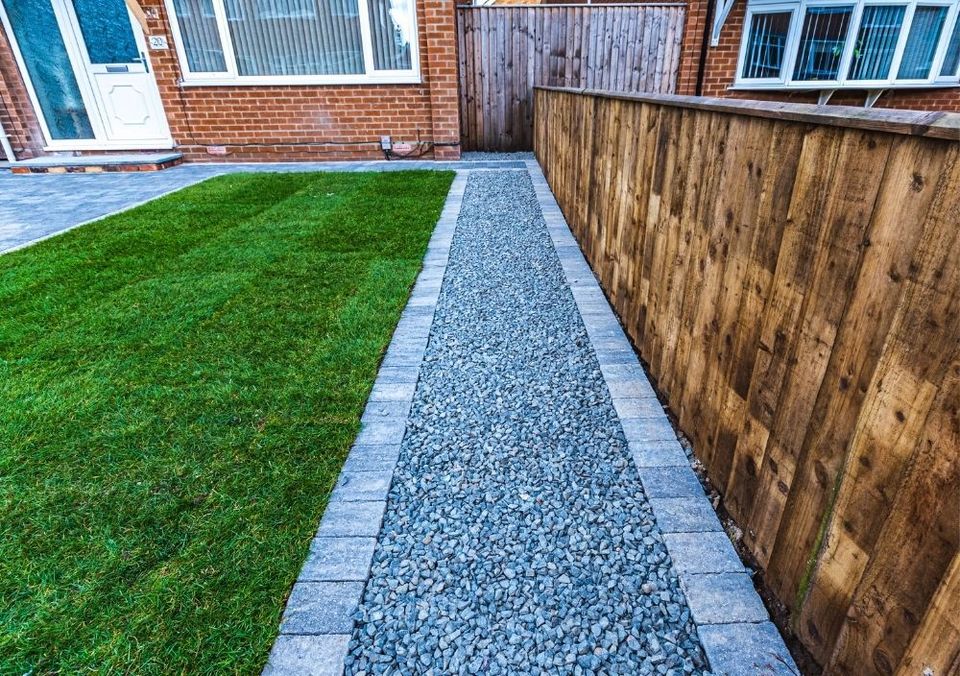 Featheredge fence beside a gravel path and a new lawn in front of a brick house
