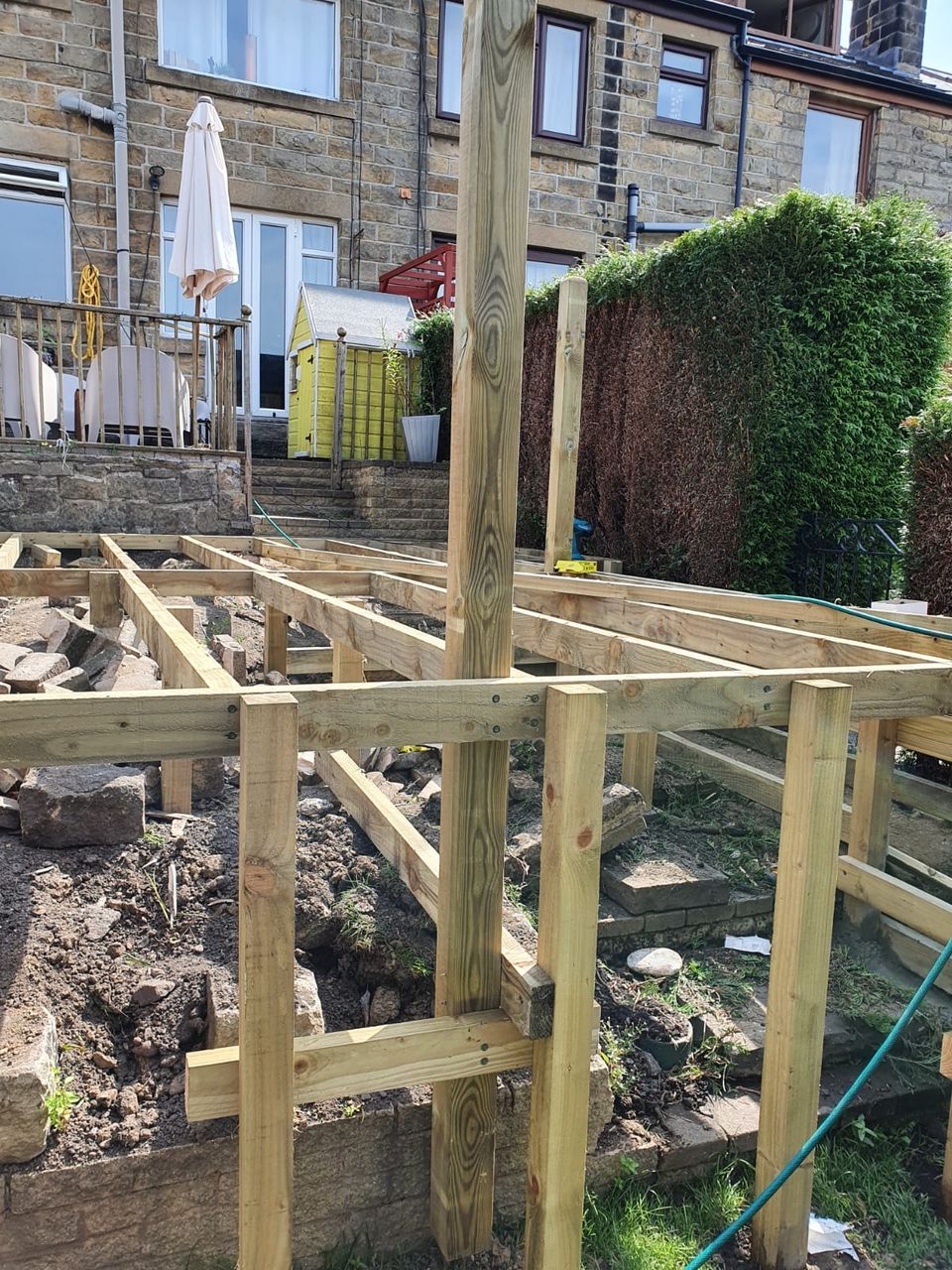 Raised deck frame and posts rising from a sloping garden in Cardiff