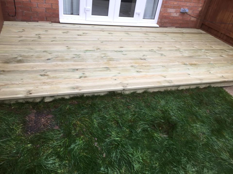 Newly laid timber deck outside patio doors with a lawn in front