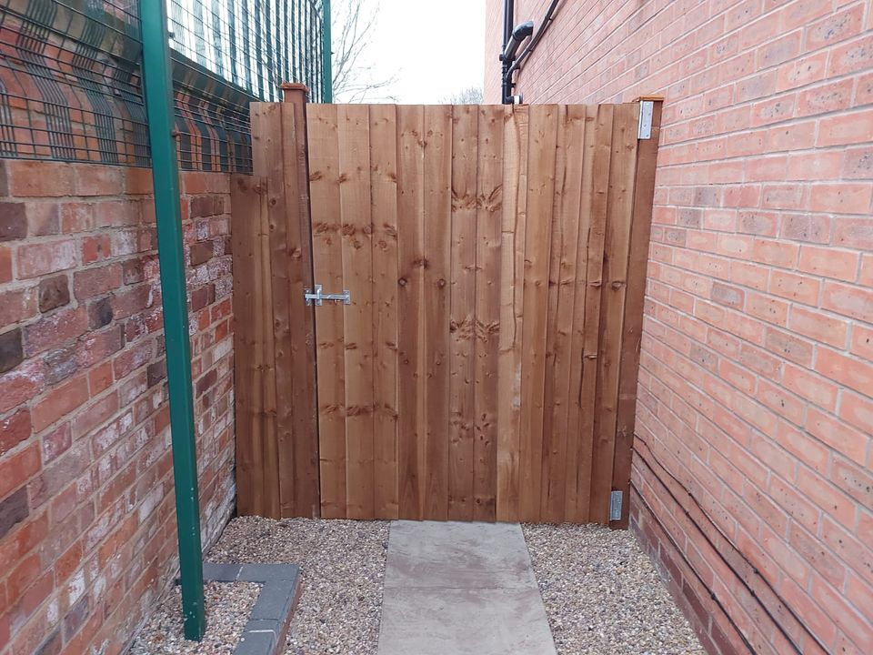 Boarded timber gate fitted between two brick walls at the end of a passage
