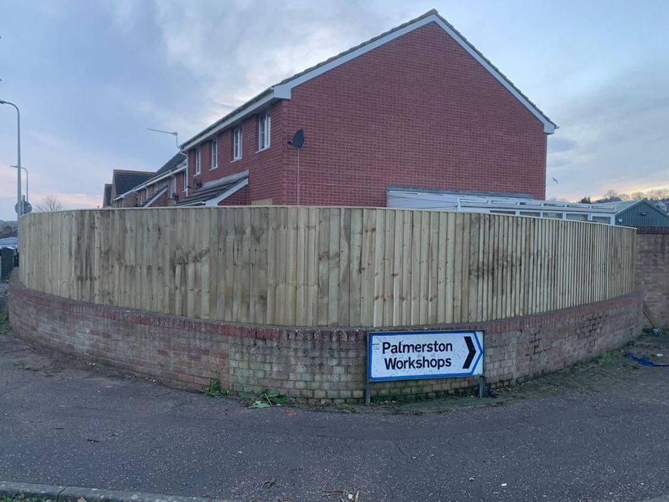 Fence panels stepped to follow a curved brick boundary wall