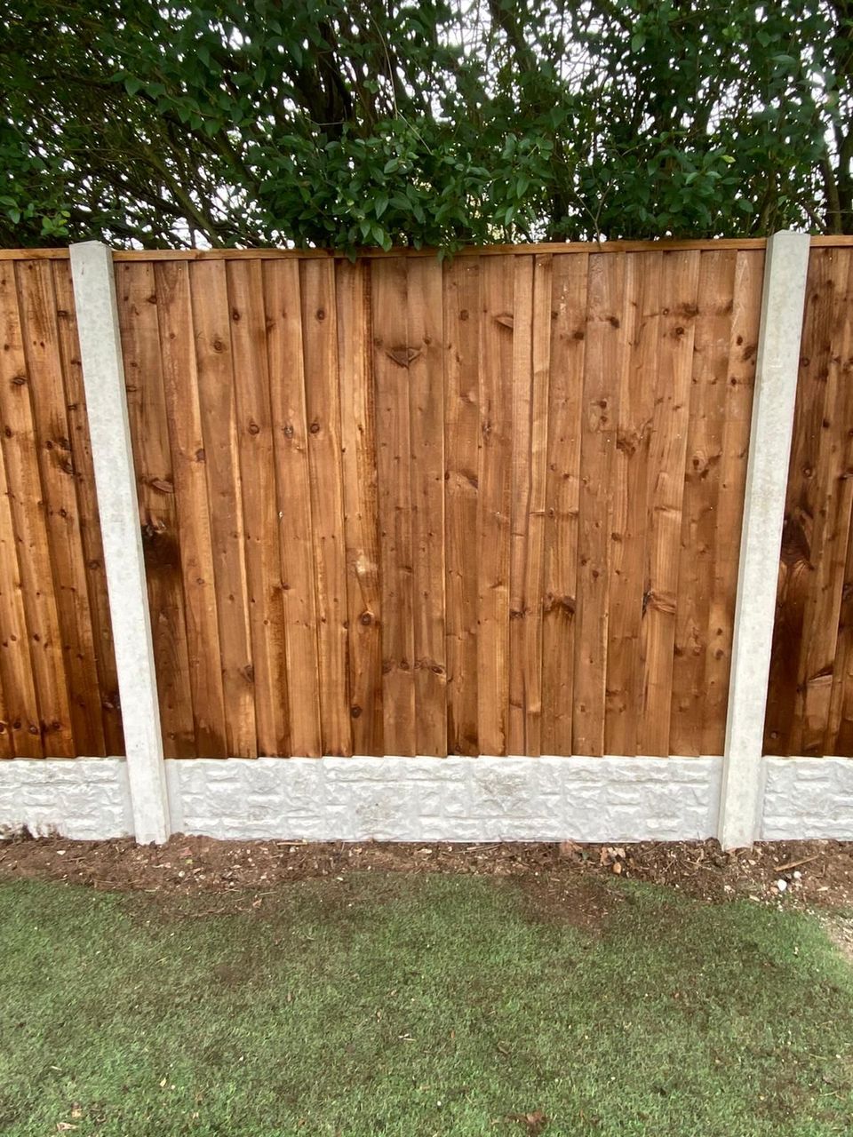 Featheredge panel between concrete posts with rock-faced concrete gravel boards