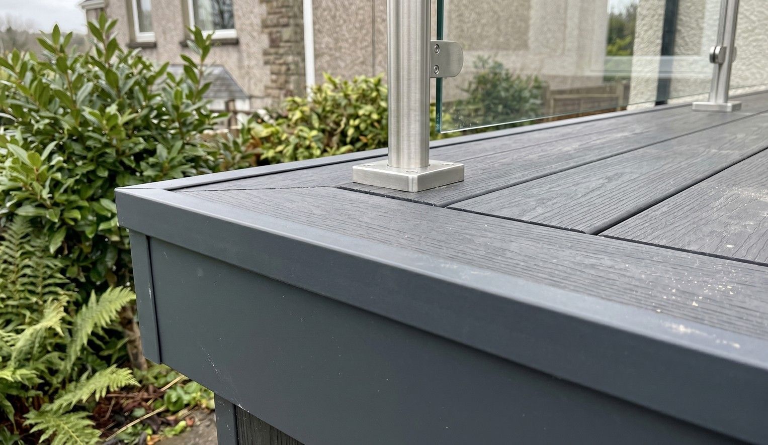 Composite decking edge fascia and glass balustrade post detail installed in Cardiff by J&Z Fencing