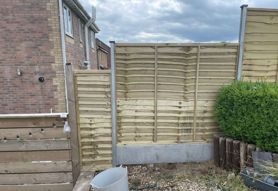 Lap fence panels meeting the house wall at a garden corner