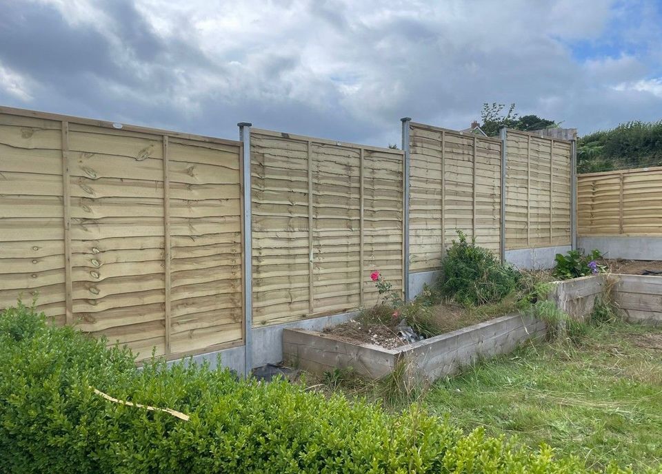 New lap fence panels on grey steel posts around a back garden with raised timber beds