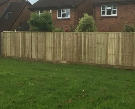 Long run of closeboard timber fencing across the back of a lawn with houses behind