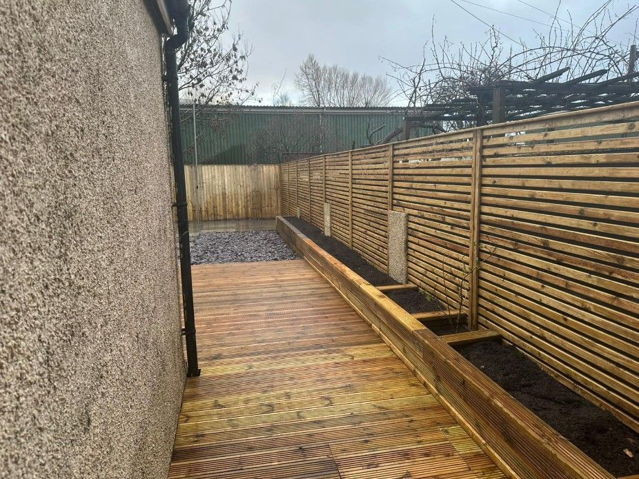 Pressure-treated timber decking installed down the side of a property to patio doors in Cardiff by J&Z Fencing