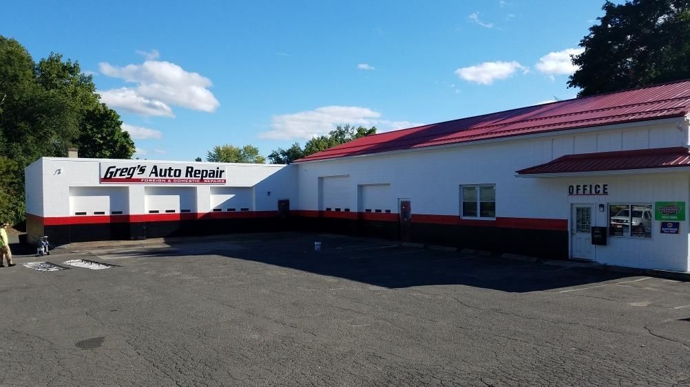 Exterior of Guy's Auto Repair building; white walls with red and black trim, red roof, blue sky  | Greg's Auto Repair