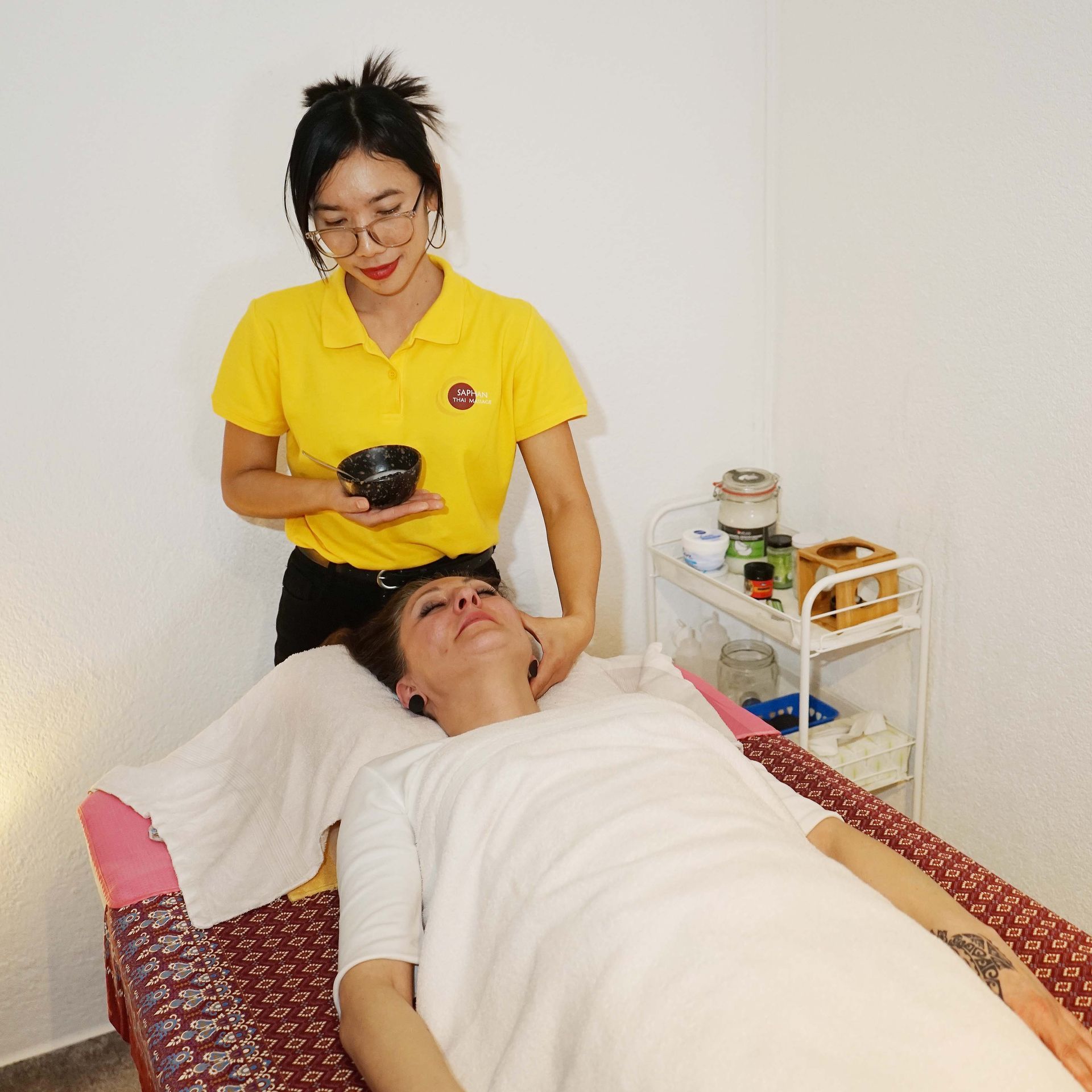 Eine Frau in einem gelben Hemd gibt einer Frau eine Massage