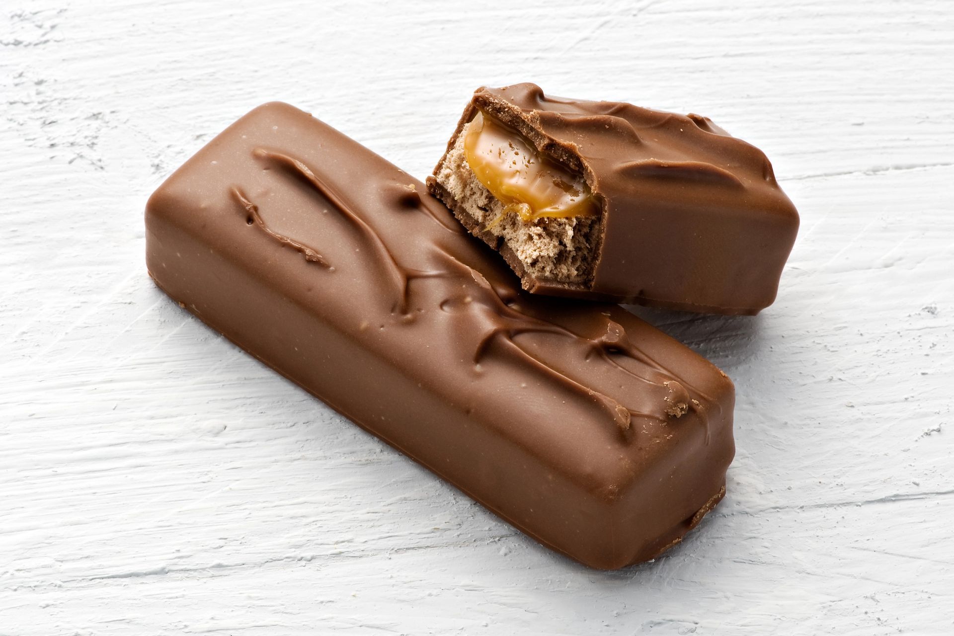 Barretta di cioccolato, una intera e una spezzata a metà, con ripieno di caramello e torrone.