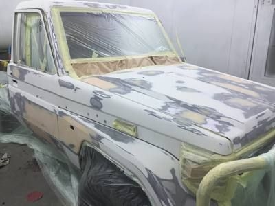 A white truck is being painted in a garage.