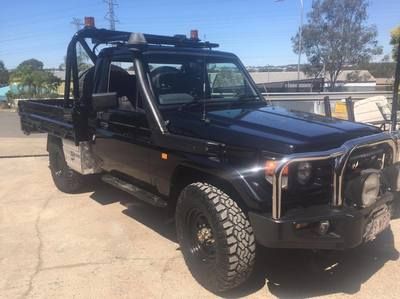 a black truck with a roof rack is parked on the side of the road .
